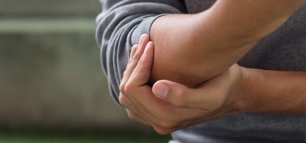 Homme qui se tient le coude pour illustrer une déchirure du biceps distal au coude