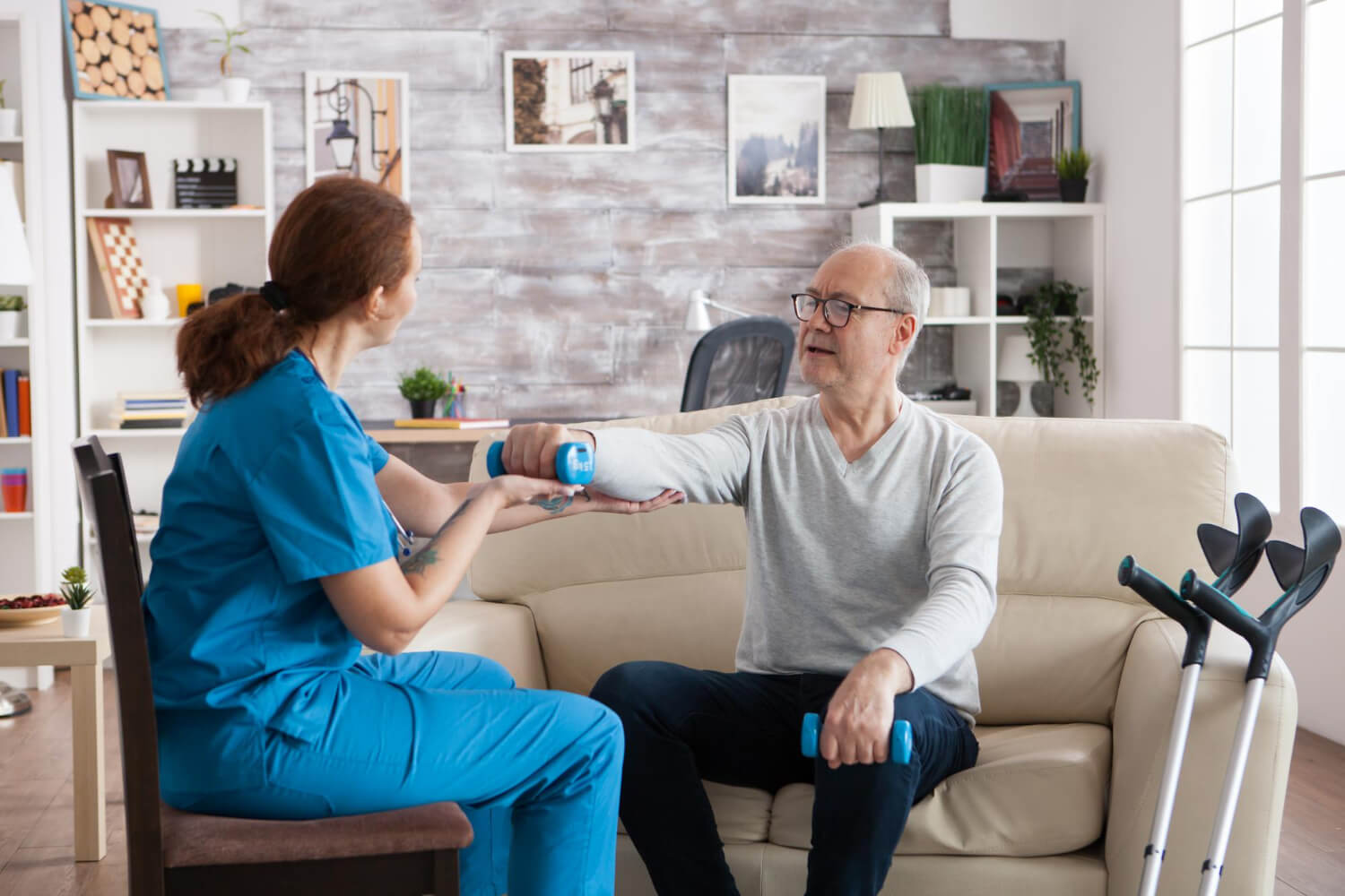 A physio helping elderly people with tennis elbow rehabilitation exercises at home