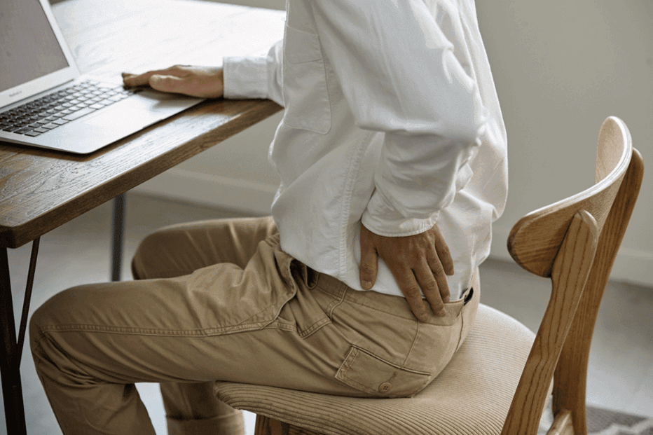 Personne assise a un bureau adoptant une posture évoquant une tendinite à la hanche